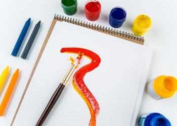 Top view of art album pages, brushes and drawing crayons